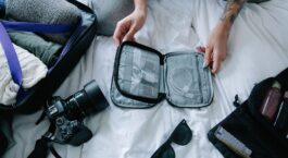Offener Koffer mit Kleidung, Kamera und organisiertem Reise-Organizer
